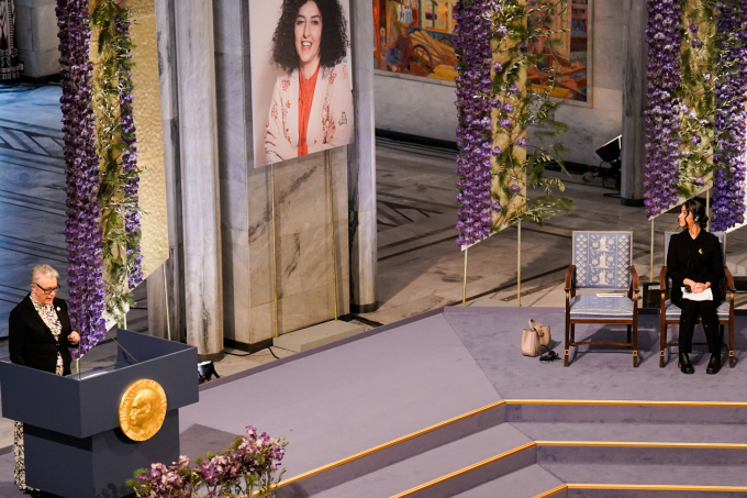 The Chair of the Norwegian Nobel Committee, Berit Reiss-Andersen, speaks during the ceremony. A large portrait of this year’s laureate hangs behind an empty chair. Photo: Fredrik Varfjell / NTB
